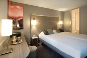 una habitación de hotel con una gran cama blanca y una mesa en Best Western Voiron Centre, en Voiron