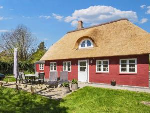 Maison rouge avec toit de chaume, table et chaises dans l'établissement Holiday home Rømø CXXI, à Kongsmark