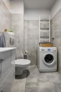 ein Badezimmer mit einer Waschmaschine und einem WC in der Unterkunft ELEGANT Apartment Mechaniczna 5W in Głogów