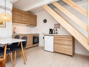 una cocina con armarios de madera y una mesa con sillas. en Holiday home Rømø XV en Rømø Kirkeby