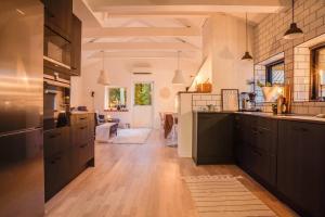a large kitchen with black cabinets and a living room at Swedish Costal Forest Hideaway in Yngsjö