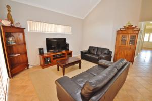 a living room with a leather couch and a tv at Kalbarri Getaway - Kalbarri WA in Kalbarri