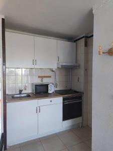a kitchen with white cabinets and a sink and a microwave at Studio in Calypso,Calahonda 200 metres from the beach in Sitio de Calahonda
