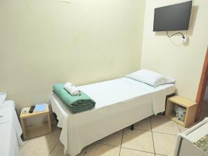 a small room with a bed and a tv at Pousada Catarina in Biguaçu