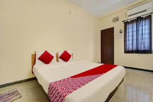 a bedroom with a large bed with red pillows at Hotel Trident Inn in Coimbatore