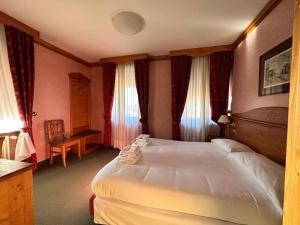 1 dormitorio con 1 cama grande y 1 silla en Hotel Alpi - Foza, en Foza