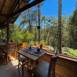uma sala de jantar com mesa e cadeiras e uma grande janela em Pousada Viviê CENTRAL em Monte Verde