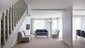 a living room with blue chairs and a staircase at Pinnacle Apartments in Canberra