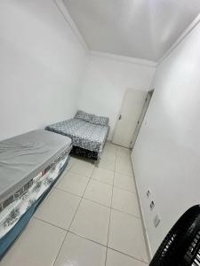 Cette petite chambre comprend deux lits et une chaise. dans l'établissement Lazer em Salvador, à Cajiru