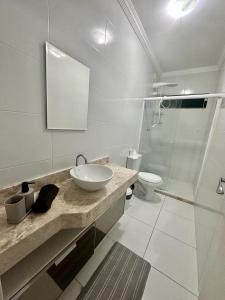 La salle de bains blanche est pourvue d'un lavabo et de toilettes. dans l'établissement Lazer em Salvador, à Cajiru