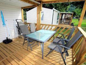 a glass table and chairs on a wooden deck at Mobile Home an der Drau in Sachsenburg