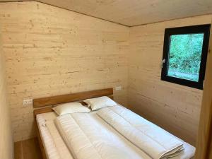 Cama en habitación pequeña con ventana en Wood Cube an der Drau en Sachsenburg