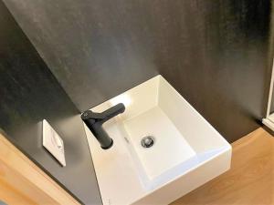 lavabo blanco con grifo negro en el baño en Wood Cube an der Drau en Sachsenburg