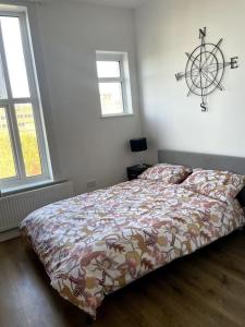 a bedroom with a bed with a comforter and two windows at Cosy 3 bedroom flat in Chatham in Chatham