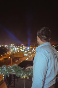 a man standing on a ledge looking at a city at night at Hotel Amazonas Suite, Suite Presidencial in Nueva Loja