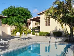 a swimming pool in front of a house with palm trees at Pousada Vale Encantado in Serra de São Bento