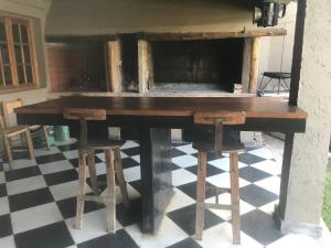 una mesa de madera con dos taburetes en un suelo a cuadros en Posada Pinar De Besares en Chacras de Coria