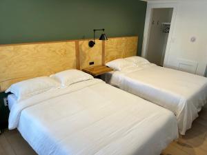 2 camas en una habitación de hotel con sábanas blancas en Happy Bear Motel, en Killington