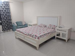 a white bedroom with a bed and a chair at Biggest Room in Sharjah in Sharjah