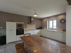 une cuisine avec des armoires blanches et une horloge au mur dans l'établissement Grande Maison de Campagne avec Jardin Clos, Proche Levroux, 12 Pers., Châteaux, Zoo de Beauval - FR-1-591-176, à Levroux