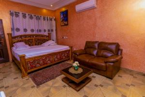 a bedroom with a bed and a couch and a chair at Kobby Keach K Hotel in Kumasi
