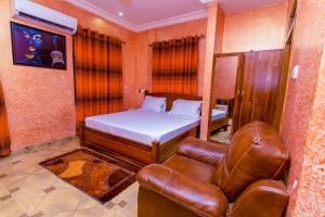 1 dormitorio con 1 cama y silla de cuero en Kobby Keach K Hotel en Kumasi