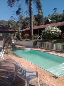 a swimming pool with a white bench next to a house at Pousada nossa senhora in Aiuruoca