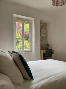 Schlafzimmer mit einem weißen Bett und einem Fenster in der Unterkunft Nuance de vert in Nevers