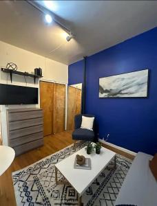 een woonkamer met een blauwe muur en een bank en een tafel bij The 30 Day Stay Vibrant House in New York