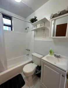 een witte badkamer met een toilet en een wastafel bij The 30 Day Stay Vibrant House in New York