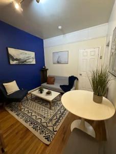 a living room with a table and a blue wall at The 30 Day Stay Vibrant House in New York