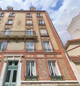 ein großes Backsteingebäude mit Fenstern und einem Balkon in der Unterkunft Paris Serenity Bedroom [Female guest only] in Courbevoie