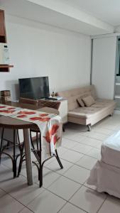 a living room with a table and a couch at Estúdio equipado no Marulhos com vista do mar e do parque aquático, à beira-mar de Muro Alto, com restaurante, estacionamento e wi-fi, a 10 minutos de carro de Porto de Galinhas in Porto De Galinhas