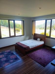ein Schlafzimmer mit einem Bett in einem Zimmer mit Fenstern in der Unterkunft Casa campo Sogamoso in Sogamoso