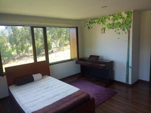 ein Schlafzimmer mit einem Bett und einem Klavier neben einem Baum in der Unterkunft Casa campo Sogamoso in Sogamoso