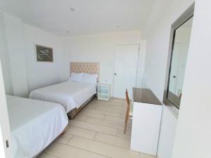 1 dormitorio con 2 camas, mesa y espejo en 202 Urban Beach, en Lurín