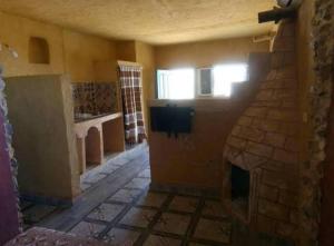 een woonkamer met een stenen open haard en een televisie bij Djerba Advent in Bou Menjel