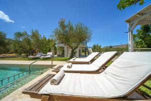 a group of lounge chairs next to a swimming pool at Villa Marian with Private Swimming Pool & Jacuzzi in Georgioupolis