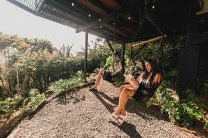 two women sitting on a swing in a garden at Ananta Forest - Glamping Dome - Hot Tub - Sunset & Gulf View in Monteverde Costa Rica