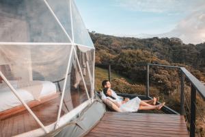 a man and a woman sitting on a deck of a yacht at Ananta Forest - Glamping Dome - Hot Tub - Sunset & Gulf View in Monteverde Costa Rica