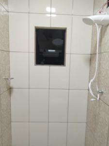 a bathroom with a tv on a white tiled wall at Lucas e Bida in Imbau