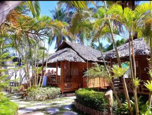 聖維森特的住宿－NATIVO D' KUBO，一座带茅草屋顶和棕榈树的度假建筑