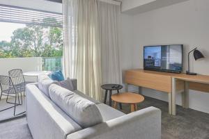 a living room with a couch and a tv at Quest Cannon Hill in Brisbane