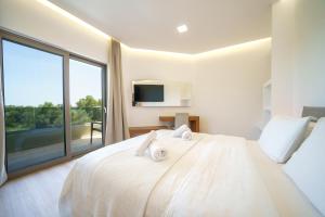 a bedroom with a white bed with a large window at Villa Marian with Private Swimming Pool & Jacuzzi in Georgioupolis