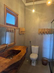 a bathroom with a wooden sink and a toilet at Pacas Suítes Casa & Chalés in Santo Amaro