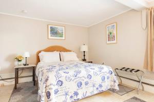 Westhampton Seabreeze Motel في Westhampton: غرفة نوم بسرير لحاف ازرق وبيض