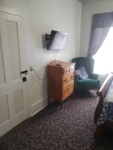 a bedroom with a dresser and a bed and a chair at Hall Place B&B in Glasgow