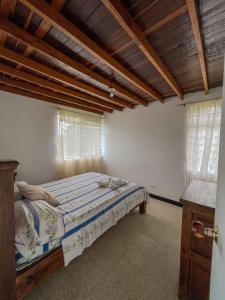 een slaapkamer met een bed in een kamer met houten plafonds bij Finca con espectacular zona verde y hermosa vista a la piedra in Guatapé