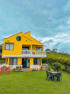 een geel huis met een tafel in de tuin bij Finca con espectacular zona verde y hermosa vista a la piedra in Guatapé