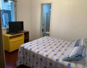 1 dormitorio con cama y vestidor con TV en Casa de férias! en Capão da Canoa